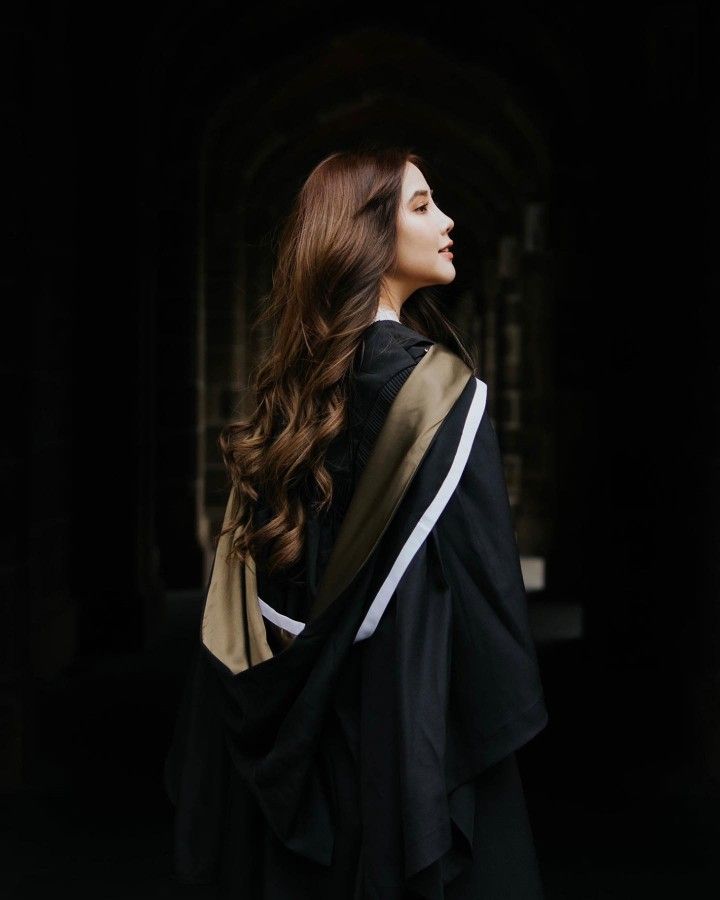 a woman with long brown hair wearing a black and gold shawl over her shoulder