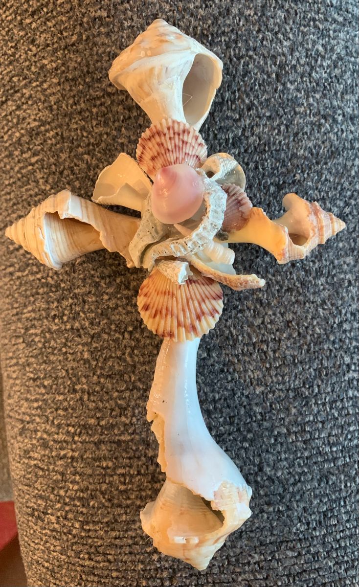 a cross made out of seashells sitting on top of a carpeted floor