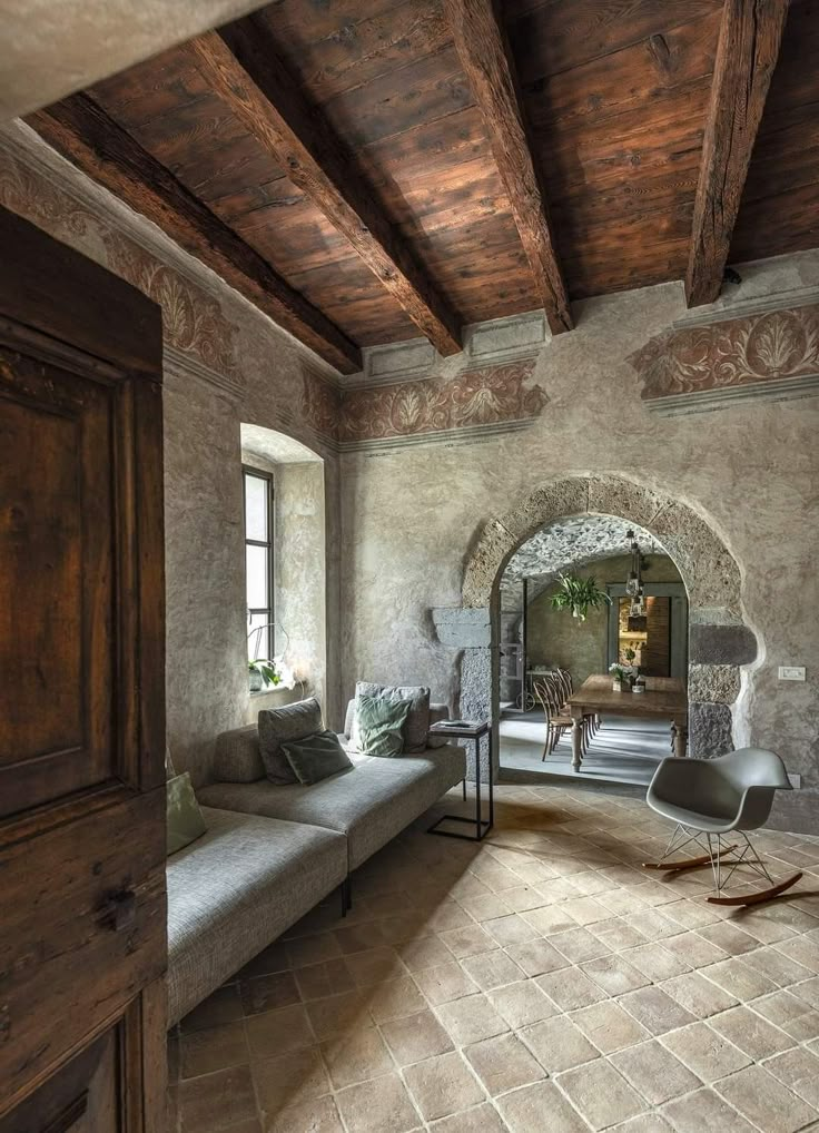 a living room with stone walls and flooring, wood trimming on the ceiling