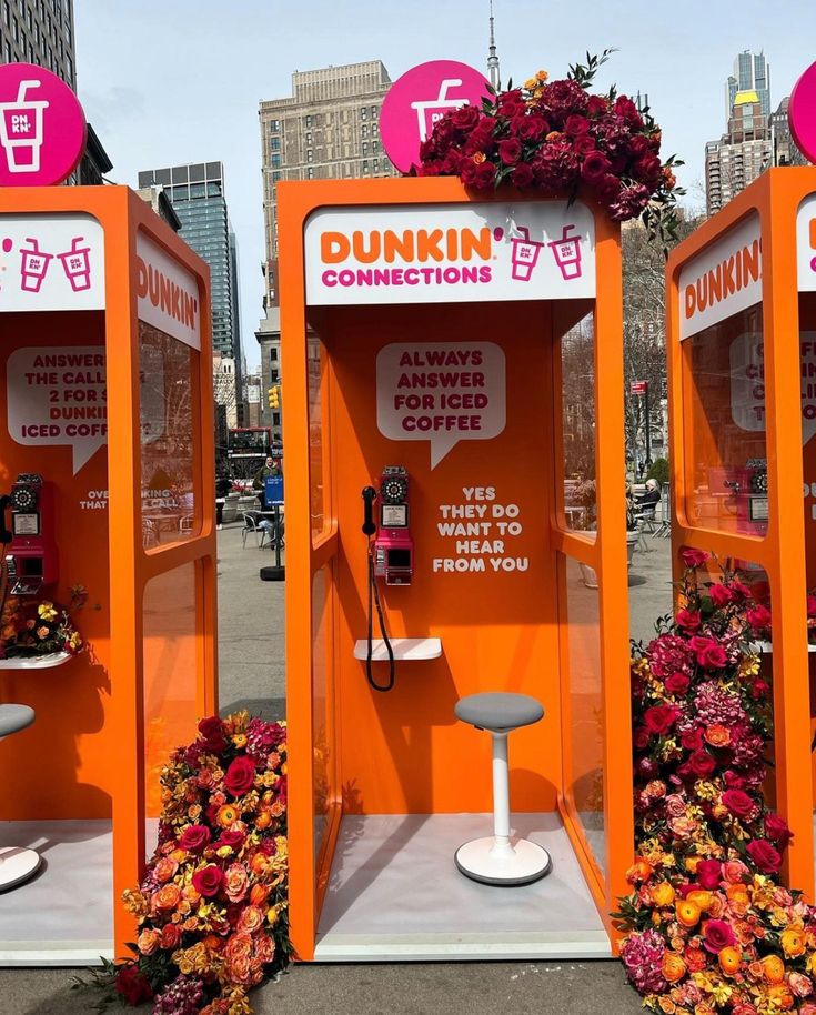 two orange phone booths with flowers in the middle and an advertisement for dunkin'donuts