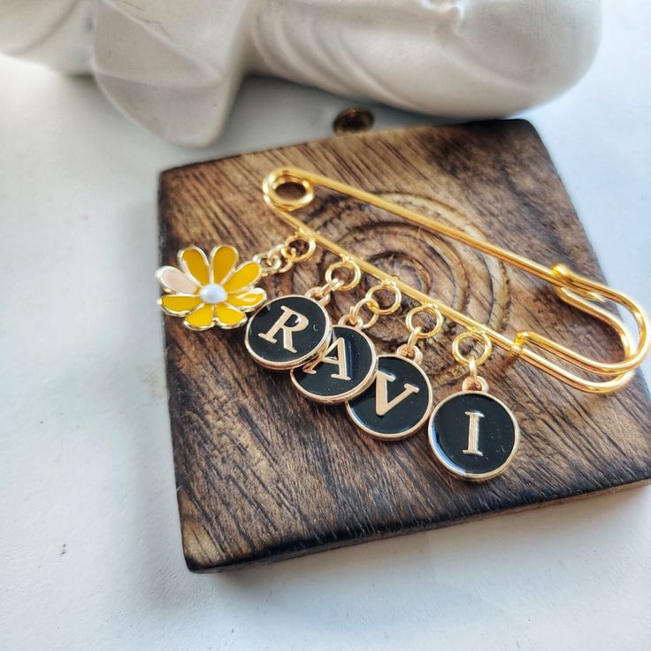 a pair of personalized bracelets with flowers on them sitting on top of a wooden plaque