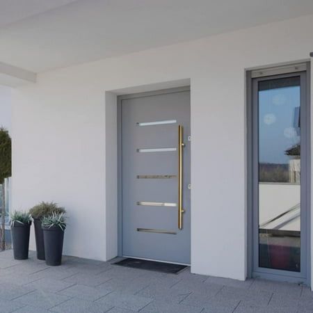 two planters with plants in front of a white wall and door on the sidewalk