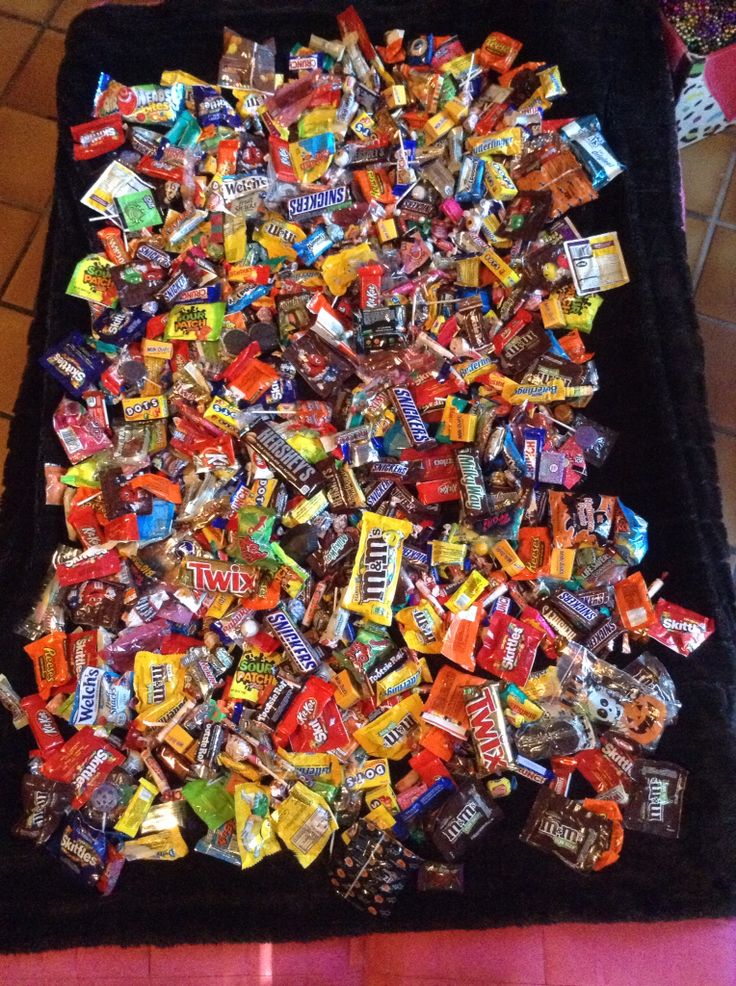 a pile of candy sitting on top of a black velvet covered bench next to a tiled floor