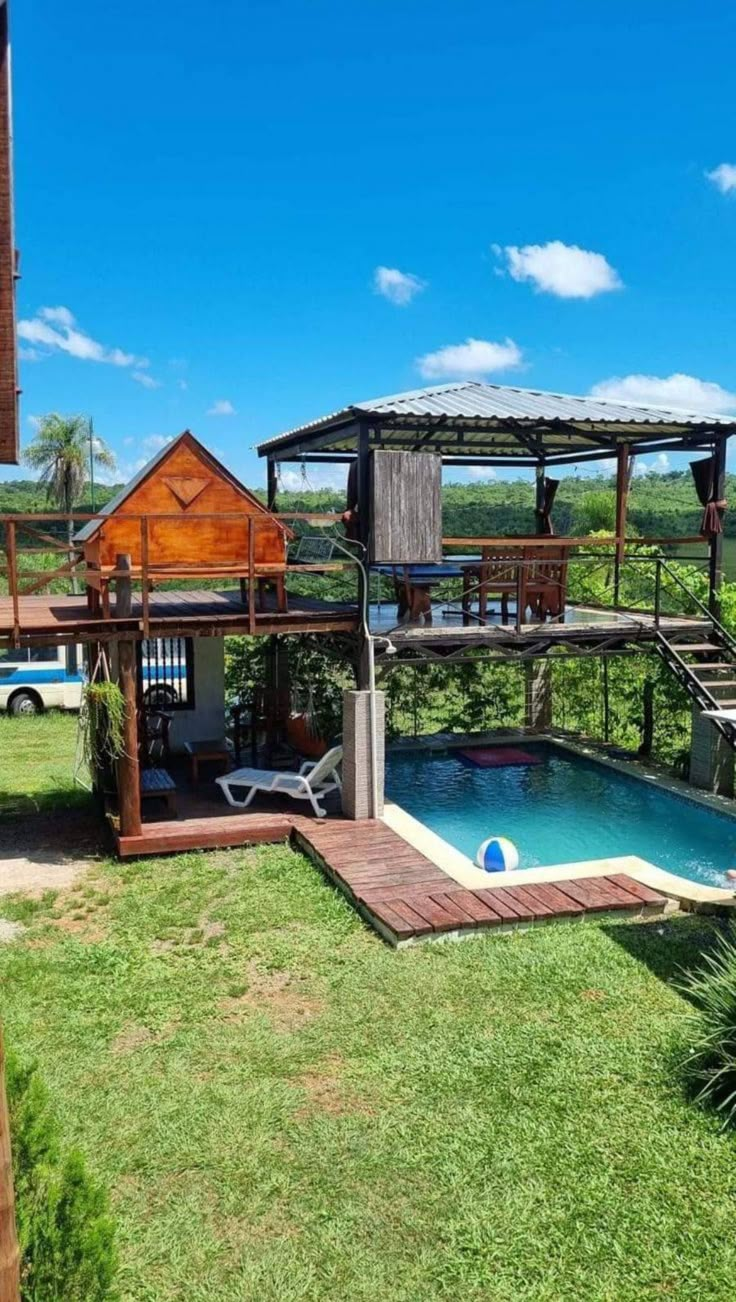 an outdoor swimming pool surrounded by greenery and wooden structure with steps leading up to it