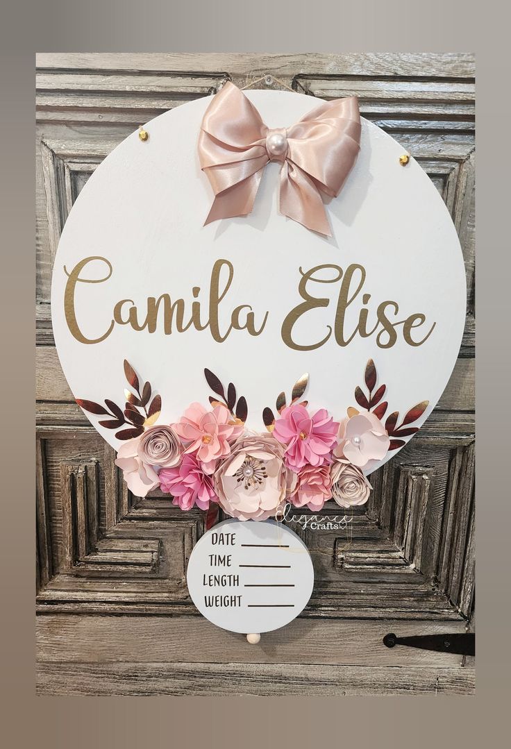 a white sign with pink flowers and a bow on it that says camila elsee