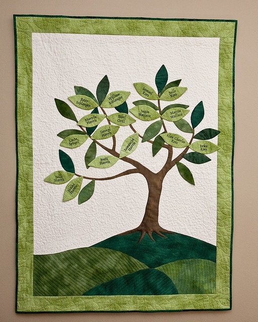 a green and white quilted wall hanging with a tree on it's side