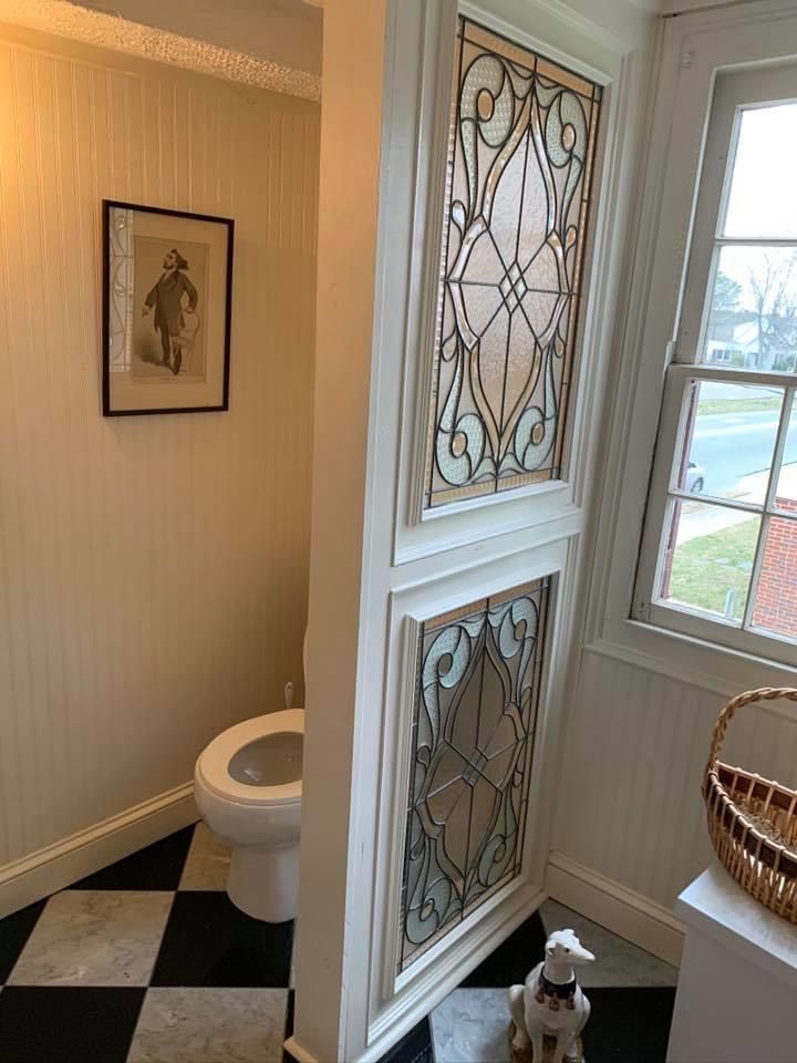 a white toilet sitting next to a window on top of a black and white checkered floor