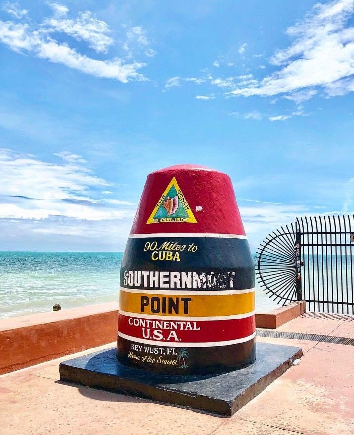 a large red and yellow cone sitting on top of a cement slab near the ocean