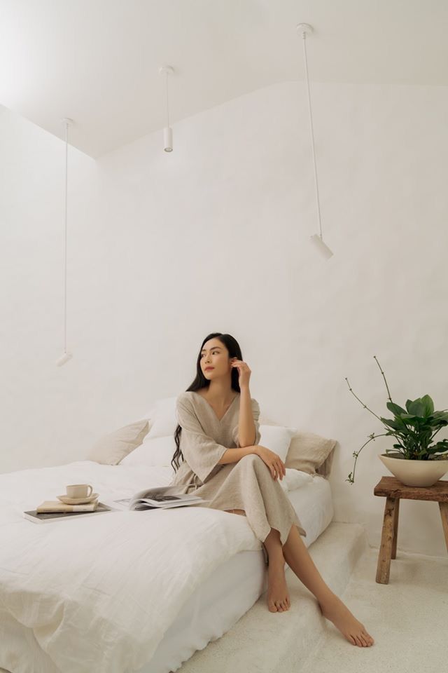 a woman sitting on top of a bed talking on a cell phone