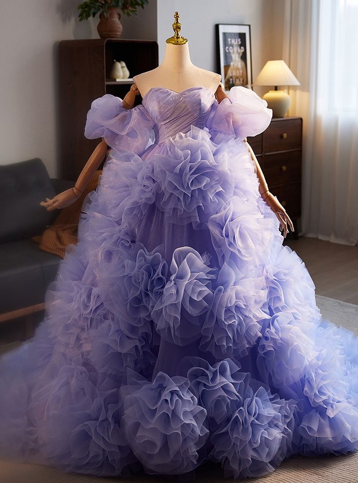 Drifting through the crowd like a dream, this prom dress is a soft symphony of lavender hues, each tier more enchanting than the last. The voluminous layers of delicate tulle cascade down to create a vision of a fairytale princess brought to life. This dress, with its floating petals of fabric and whisper-soft texture, feels like a cloud caught in the tender grip of a gentle breeze. Every pleat, every ruffle, speaks of elegance and softness, inviting the wearer to revel in a night of dancing and Puffy Purple Dress, Voluminous Layers, Floating Petals, Ruffle Tulle Dress, Purple Tulle, Layered Ruffle Dress, Fairytale Princess, Prom Dress Plus Size, Satin Tulle