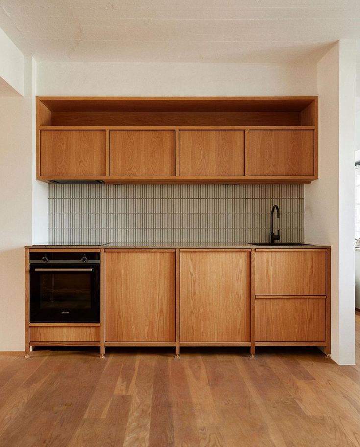 an empty kitchen with wooden cabinets and wood floors