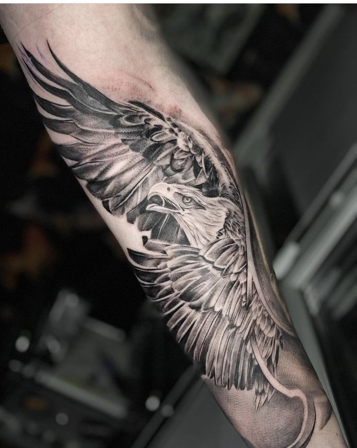 an eagle tattoo on the arm with black and grey ink, done by michael schneck