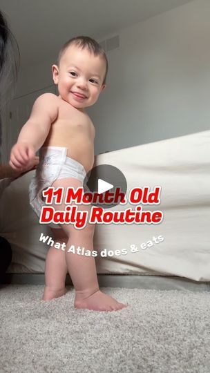 a baby in diapers standing on the floor next to a woman with her arm around him