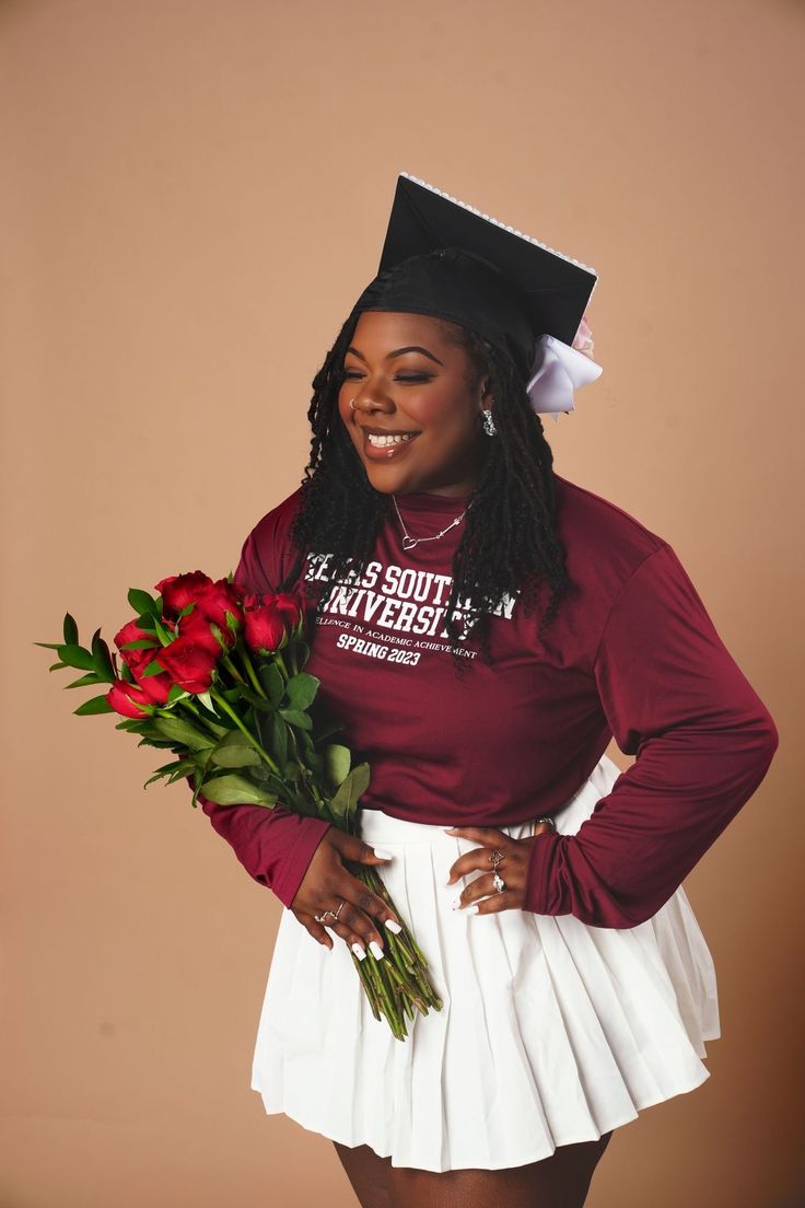 a woman in a graduation cap and gown holding roses