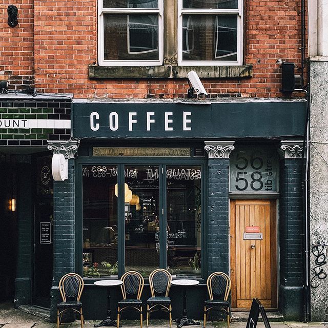 the outside of a coffee shop with tables and chairs