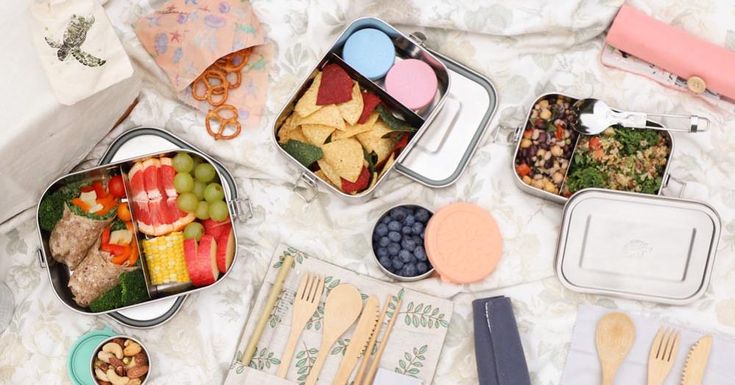 an assortment of food is laid out on a bed with utensils and napkins