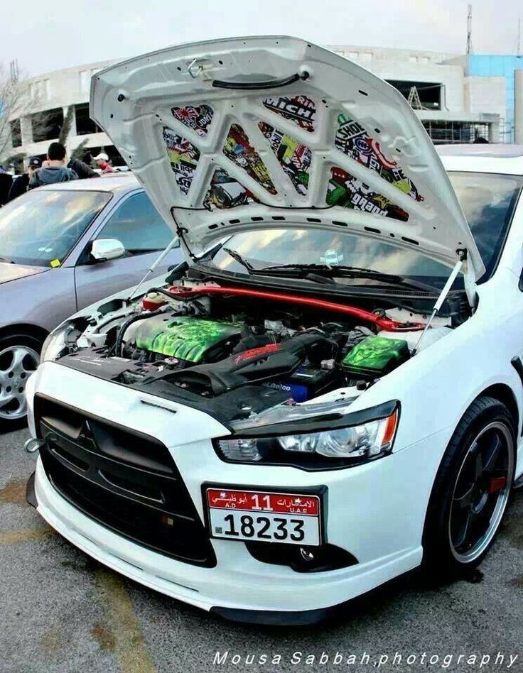 a white car with its hood open in a parking lot