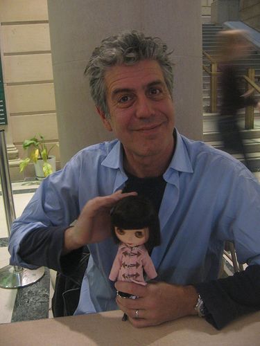 a man sitting at a table with a doll in front of him