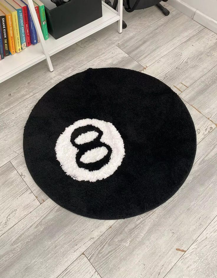 a black and white rug with the letter s on it in front of a bookshelf