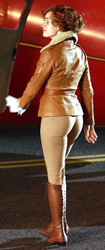 a woman in tights and boots standing next to a red airplane with her hand on the door