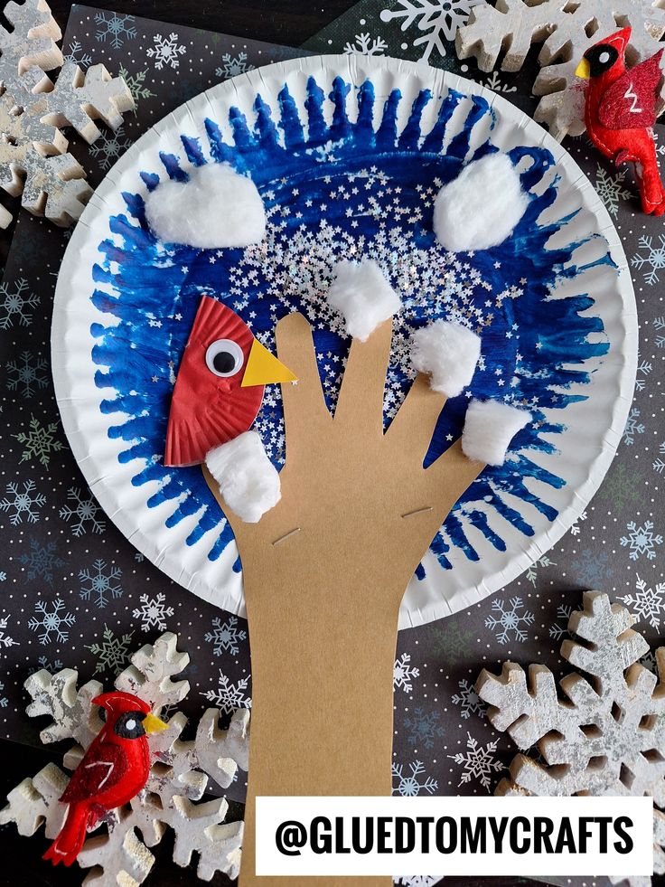 a paper plate that has snowflakes on it and a hand holding a bird