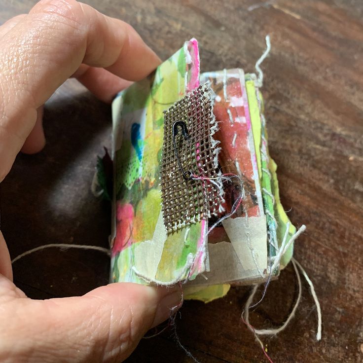 someone is stitching together fabric and thread to make a miniature house ornament