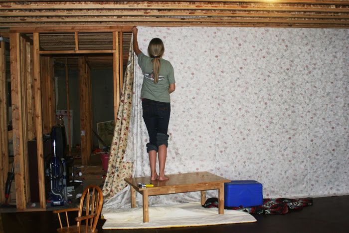 a woman standing on top of a wooden table in a room with wallpapered walls