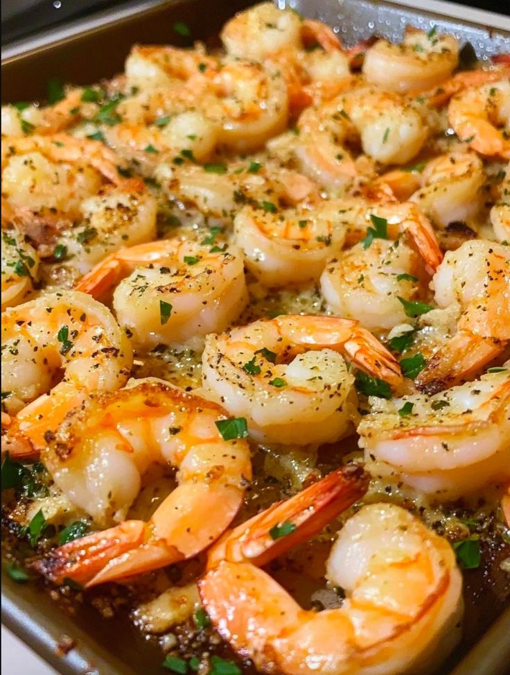 a pan filled with cooked shrimp and garnished with parsley sprinkled on top