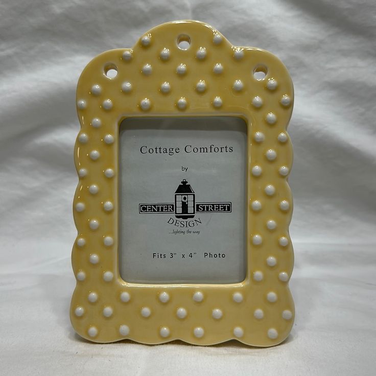 a yellow frame with white pearls on the edges and an image of a lighthouse in the middle