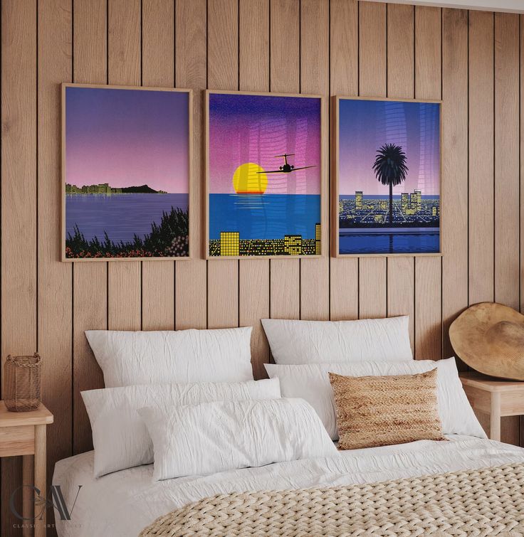 three paintings hang on the wall above a bed