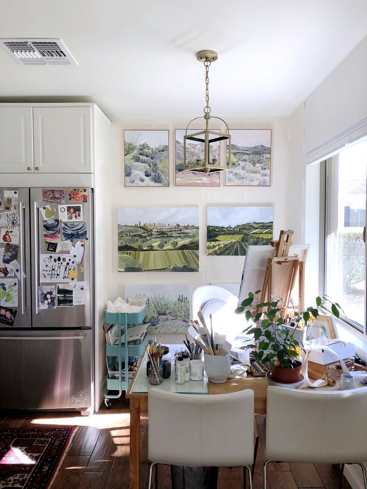 a kitchen filled with lots of clutter and art on the wall next to a refrigerator