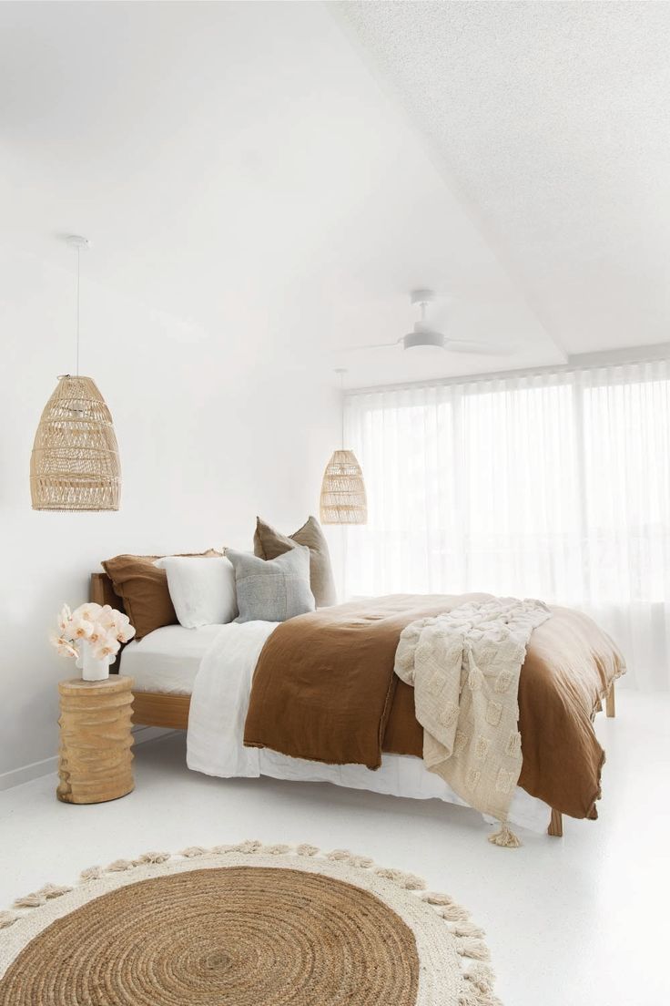 a bedroom with a bed, rugs and two hanging lamps on the wall above it