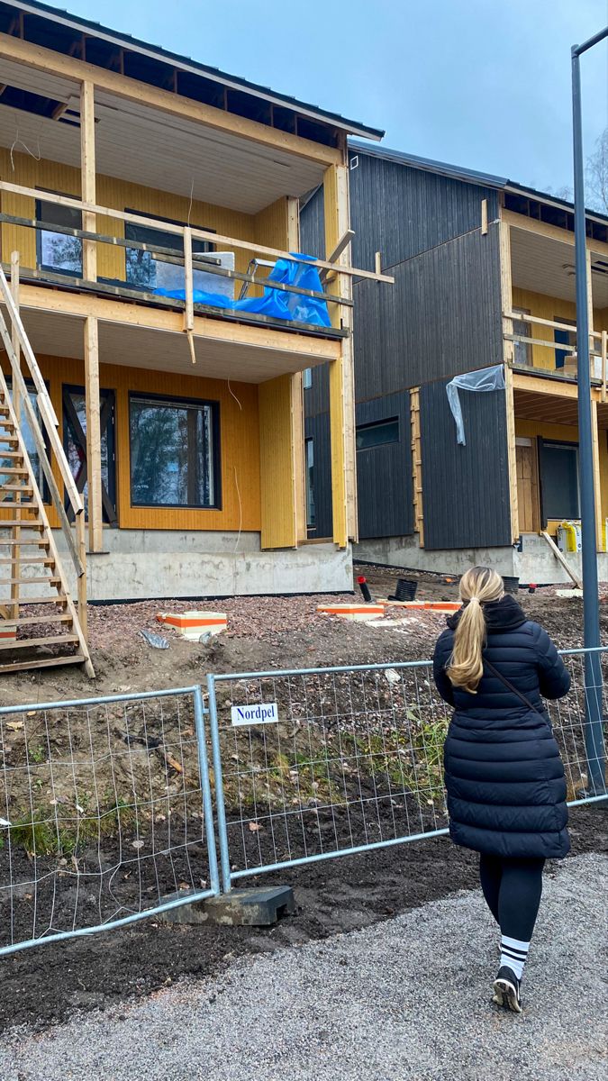 a woman is walking in front of a building under construction with stairs and railings