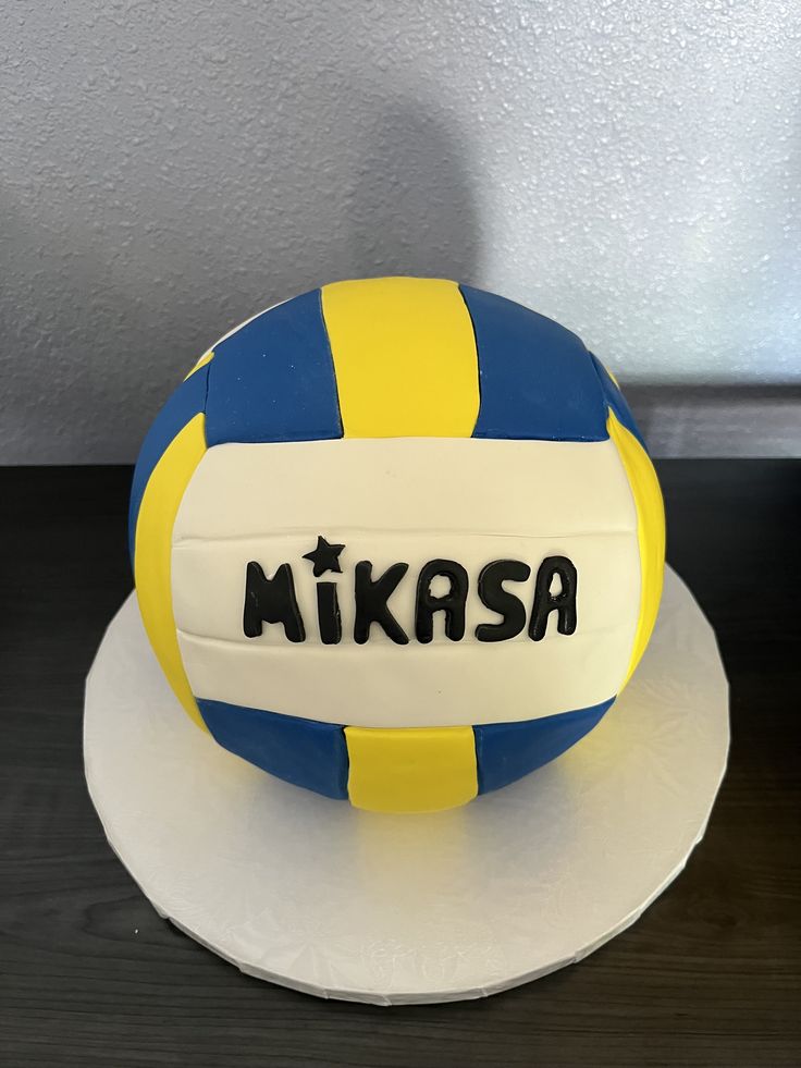 a volleyball cake with the name mikasa on it, sitting on top of a table