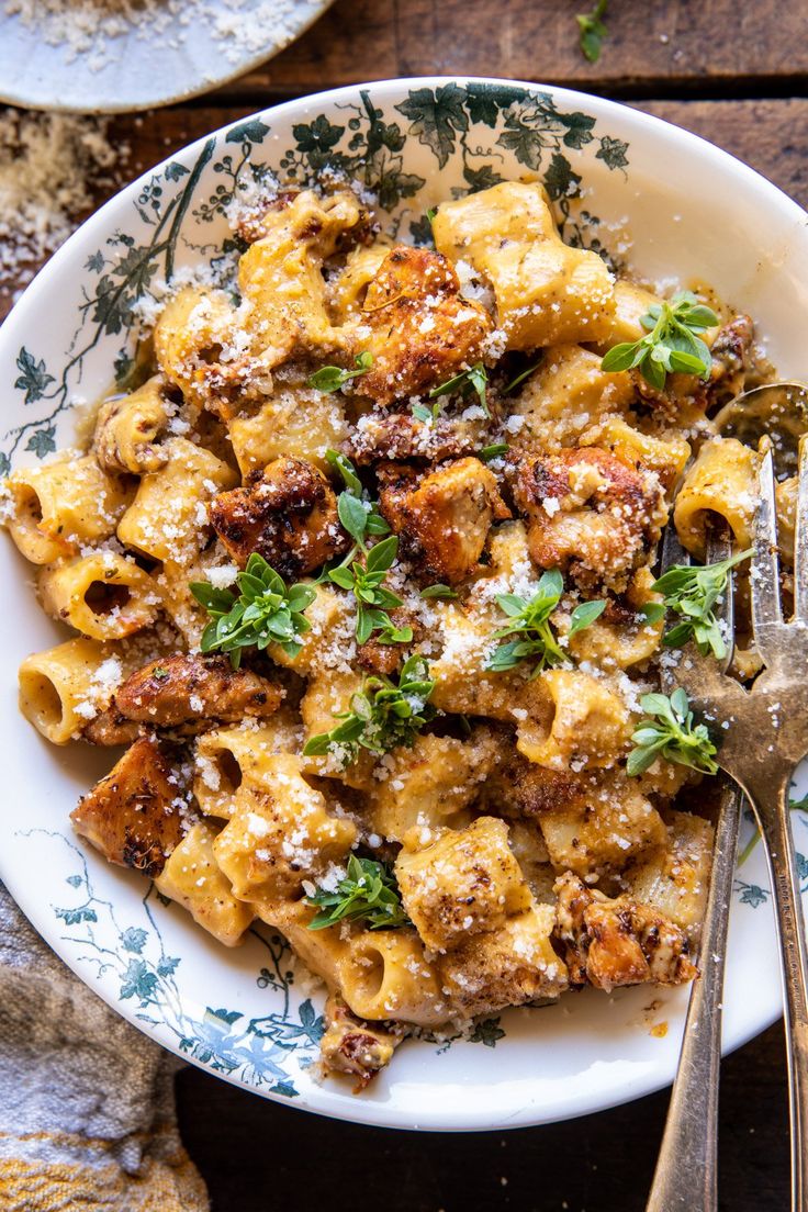 a white plate topped with pasta covered in sauce and parsley next to a fork