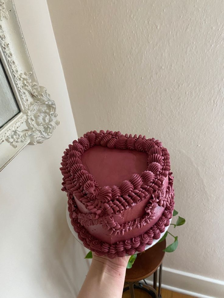 a person holding a cake in the shape of a heart on top of a table