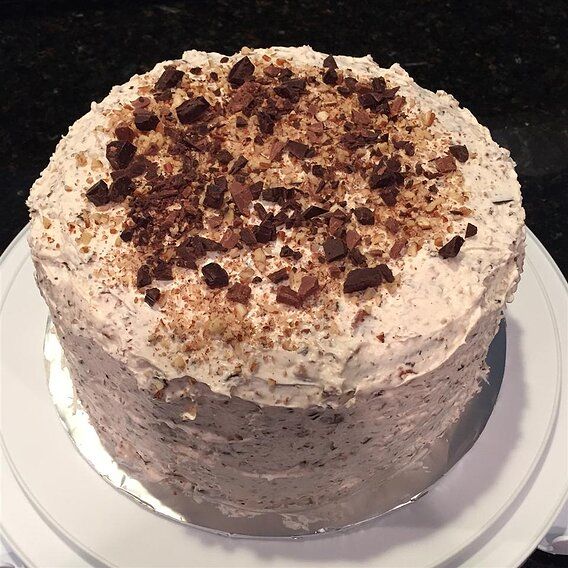 a cake sitting on top of a white plate covered in frosting and toppings