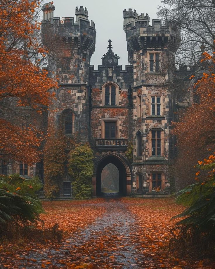 an old castle in the fall with leaves on the ground and trees around it's entrance