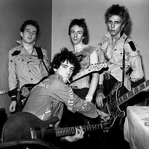 an old black and white photo of four young men with guitars