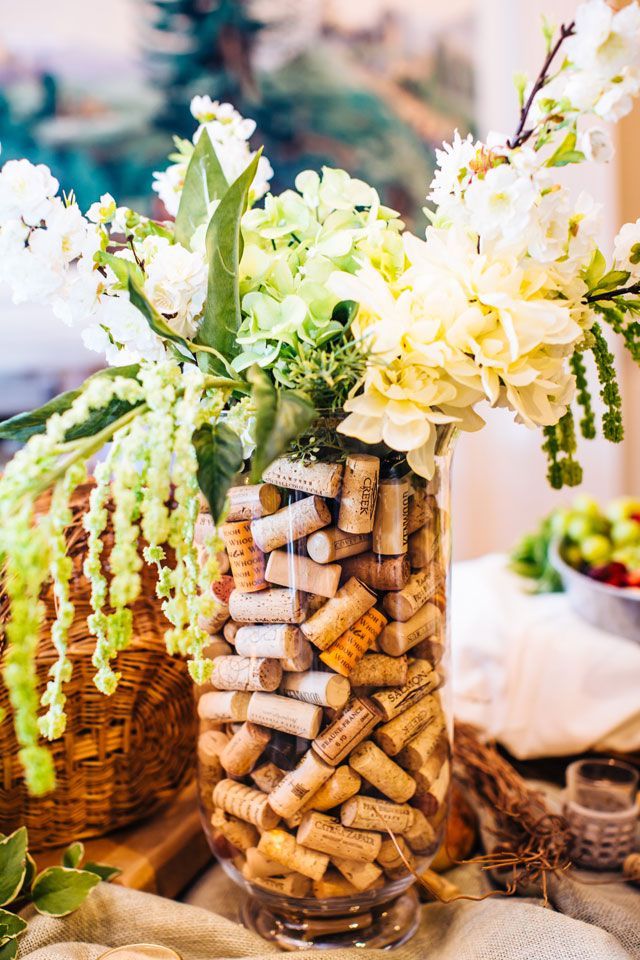 a vase filled with lots of wine corks on top of a table next to flowers