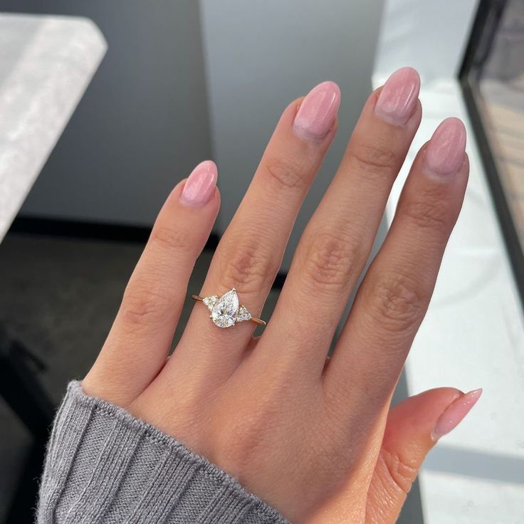 a woman's hand with a ring on top of her finger and a diamond in the middle