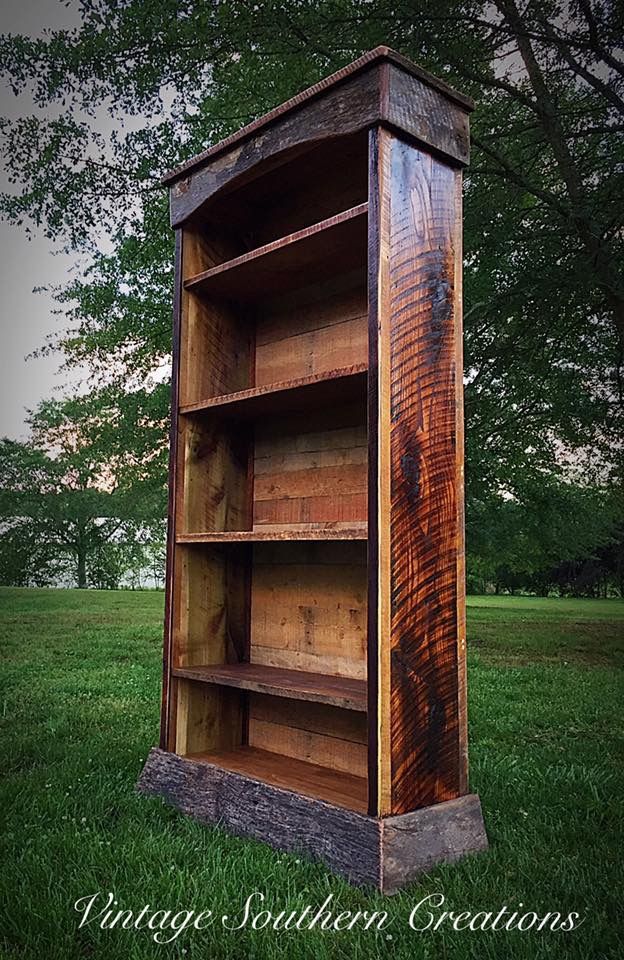 a wooden book shelf sitting on top of a lush green field