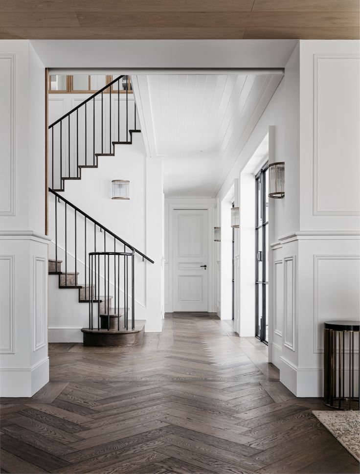 an empty room with wooden floors and white walls, stairs leading to the second floor