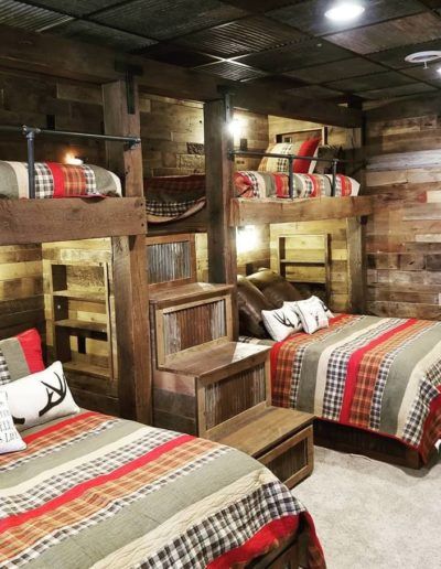 two beds in a room with wooden walls and bunk beds on each side, one is made out of wood planks