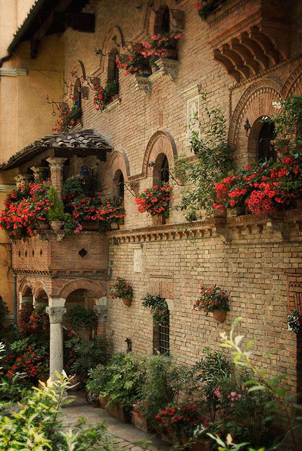 an old building with flowers growing on the windows