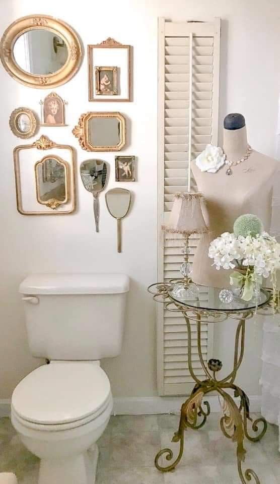 a white toilet sitting in a bathroom next to a table with flowers and mirrors on it