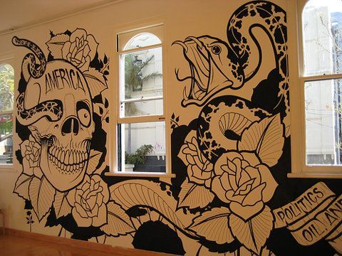 a wall painted with black and white flowers, skulls and roses on it's side