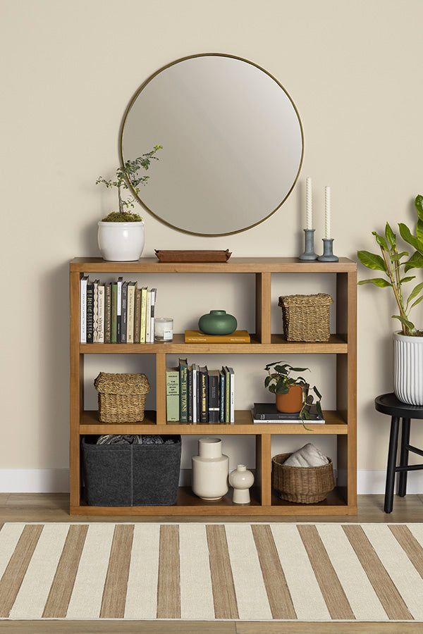 a bookshelf filled with lots of books next to a mirror and potted plant