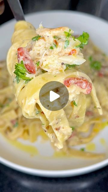 a person is holding a fork full of pasta with shrimp and tomatoes on it in a white bowl