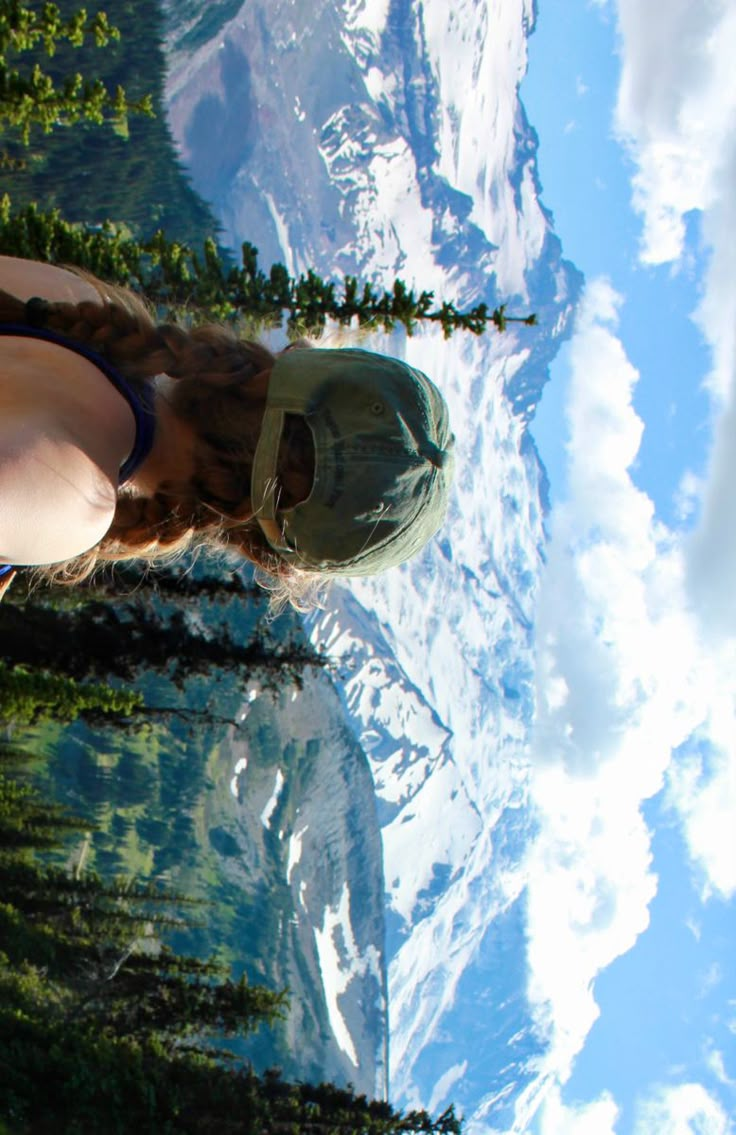 a woman standing in front of mountains and trees